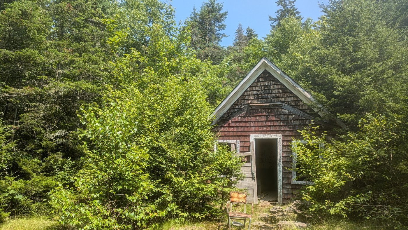 rusted chair outside an old shack in the woods on Mount Chase in Maine